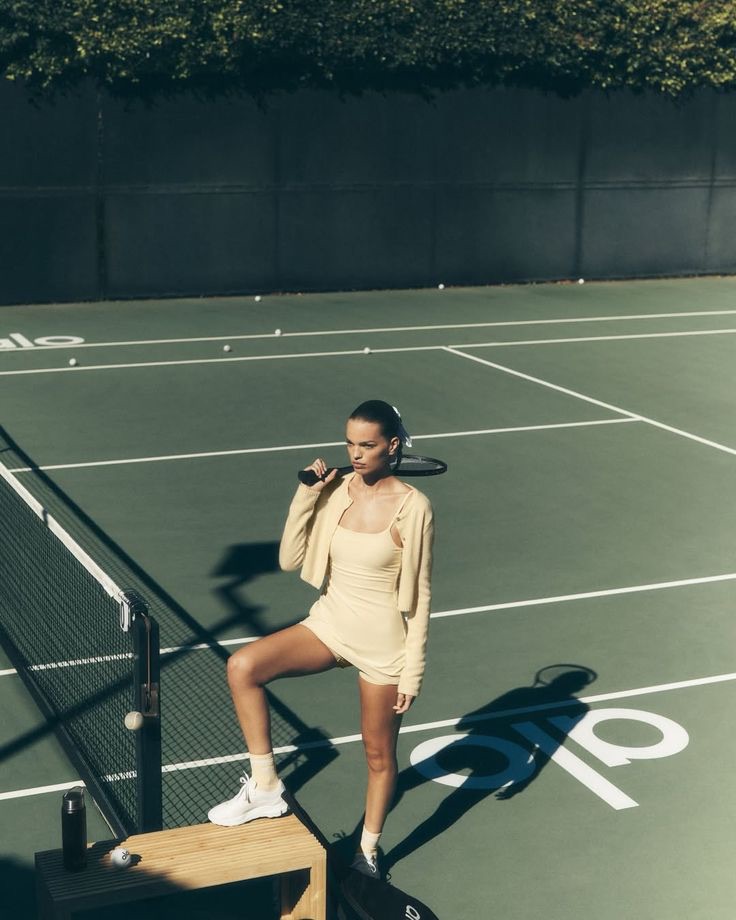 Alo campaign photography: a figure on a sunlit tennis court in matching cream separates