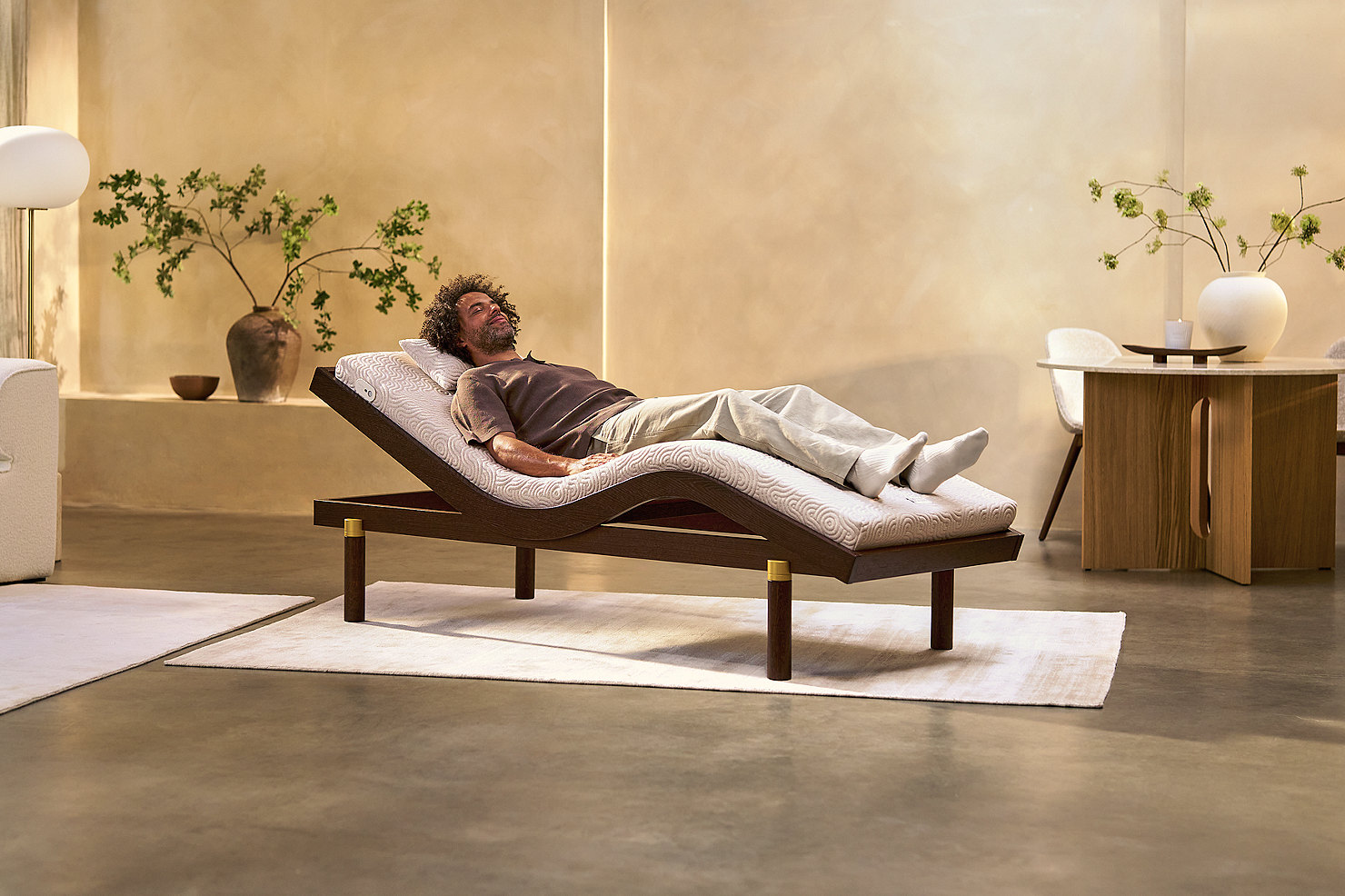 A man resting on the Intelligent Wellbeing Mat on its Zero-G frame in a warm, calm living room